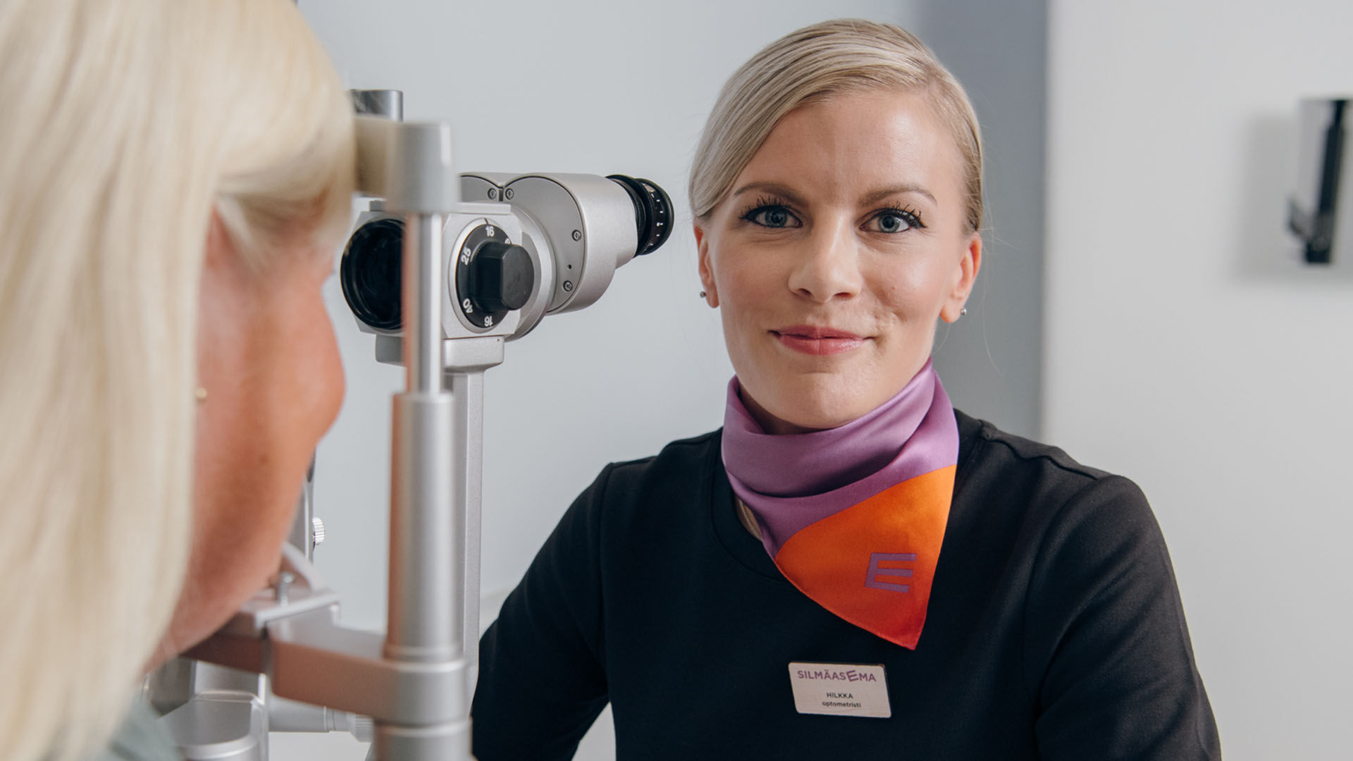Optikko suorittamassa n&auml;&ouml;ntutkimusta asiakkaalle.